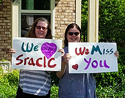 two women holding signs that read we love sraclc and we miss you