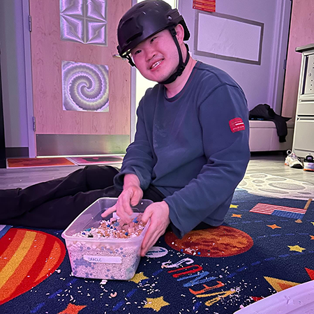 boy in sensory room playing with small paper clippings

