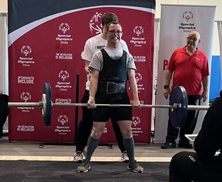 Young Man holding a deadlift for special olympics