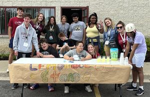 A group of teens and adults at a lemonade  stand