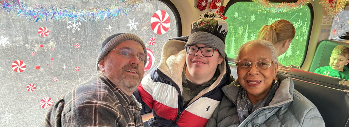 sraclc-christmas-train-family-event Adult participants smile together aboard a Christmas train during a family holiday event hosted by SRACLC.