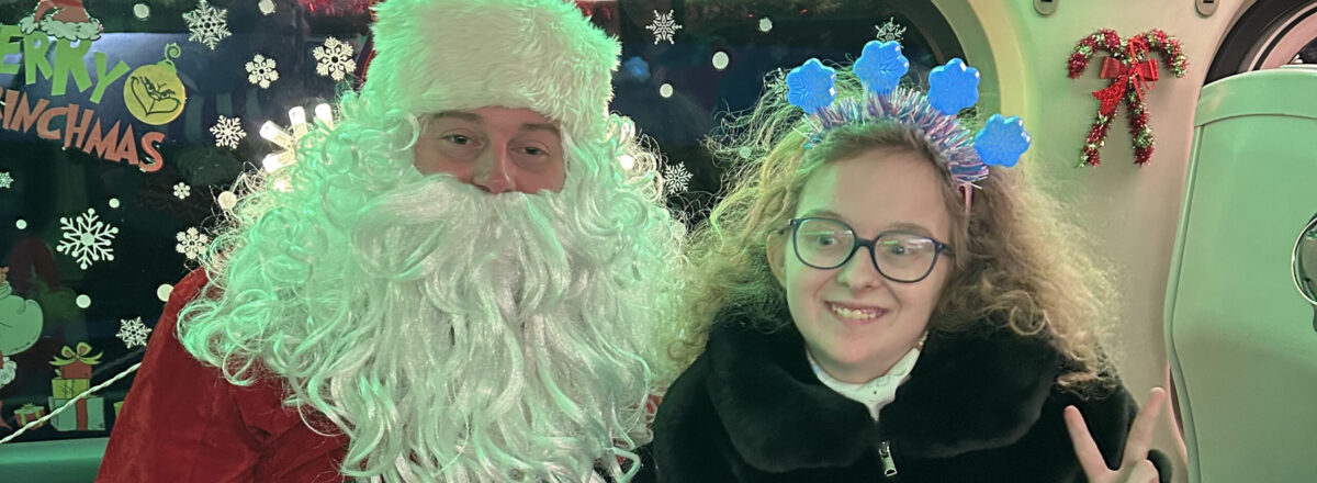 sraclc-christmas-train-santa-holiday-event Santa smiles alongside an adult female participant making a peace sign at SRACLC’s Christmas train event.